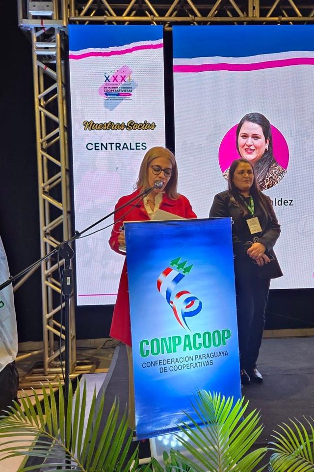 Cynthia Noguera conduciendo desde el atril de CONPACOOP junto a una disertante